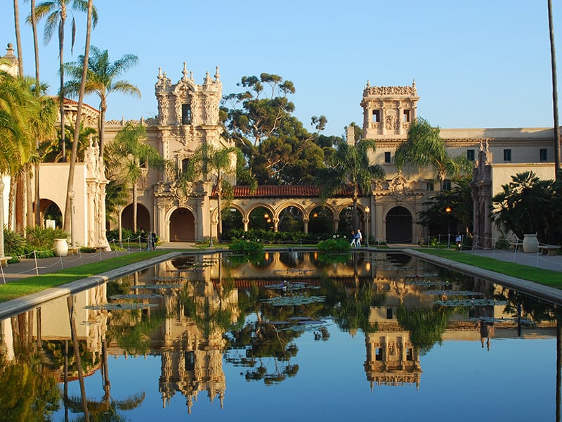 A large building with Spanish-style architecture and a reflection pool in front of it.